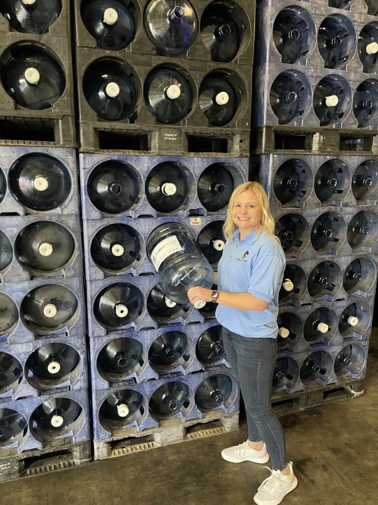 TruBlue Water team member with racks of 5 gallon bottles