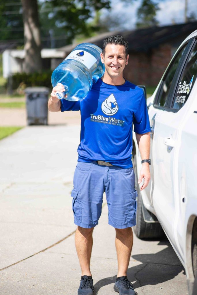 TruBlue Water driver carrying a 5 gallon bottle of artesian water