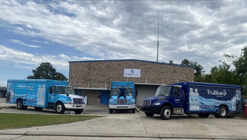TruBlue Water delivery trucks parked outside the warehouse