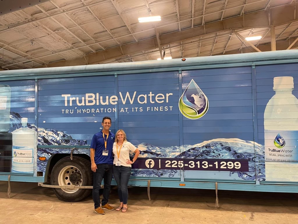 TruBlue Water team in front of a branded delivery truck at an event